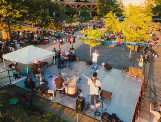 A group of people playing music on a stage at a festival.