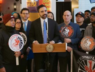 Mayor Zohran Mamdani stands with delivery app drivers.