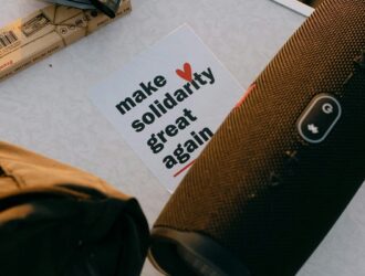 A handwritten-style card reading "make solidarity great again" with a red heart.